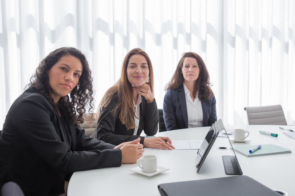 Tres mujeres conversando alrededor de una mesa en un ambiente de feria